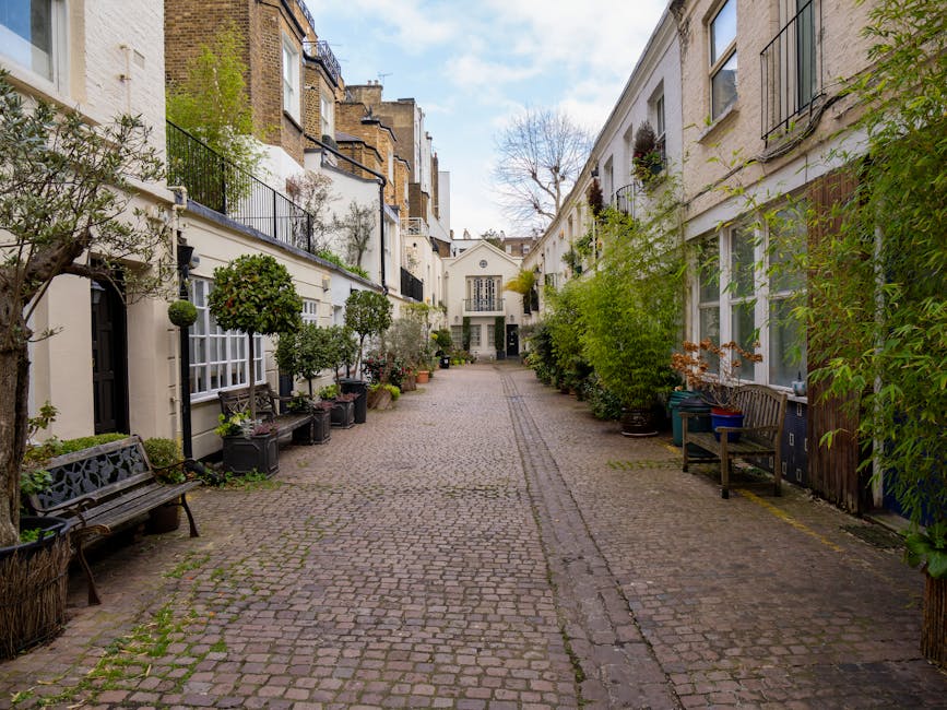 The image depicts a row of colorful Victorian-style terraced houses on a residential street, with facades painted in pastel shades of blue, yellow, and lavender. Each property has white-framed sash wi